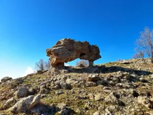 A rock formation on top of a rocky hill.