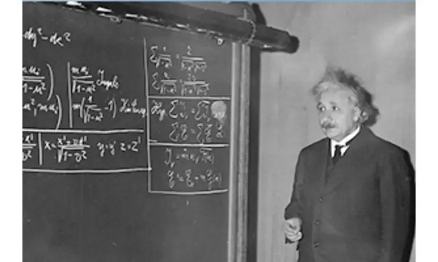 Albert Einstein standing by a blackboard full of special relativity formulas